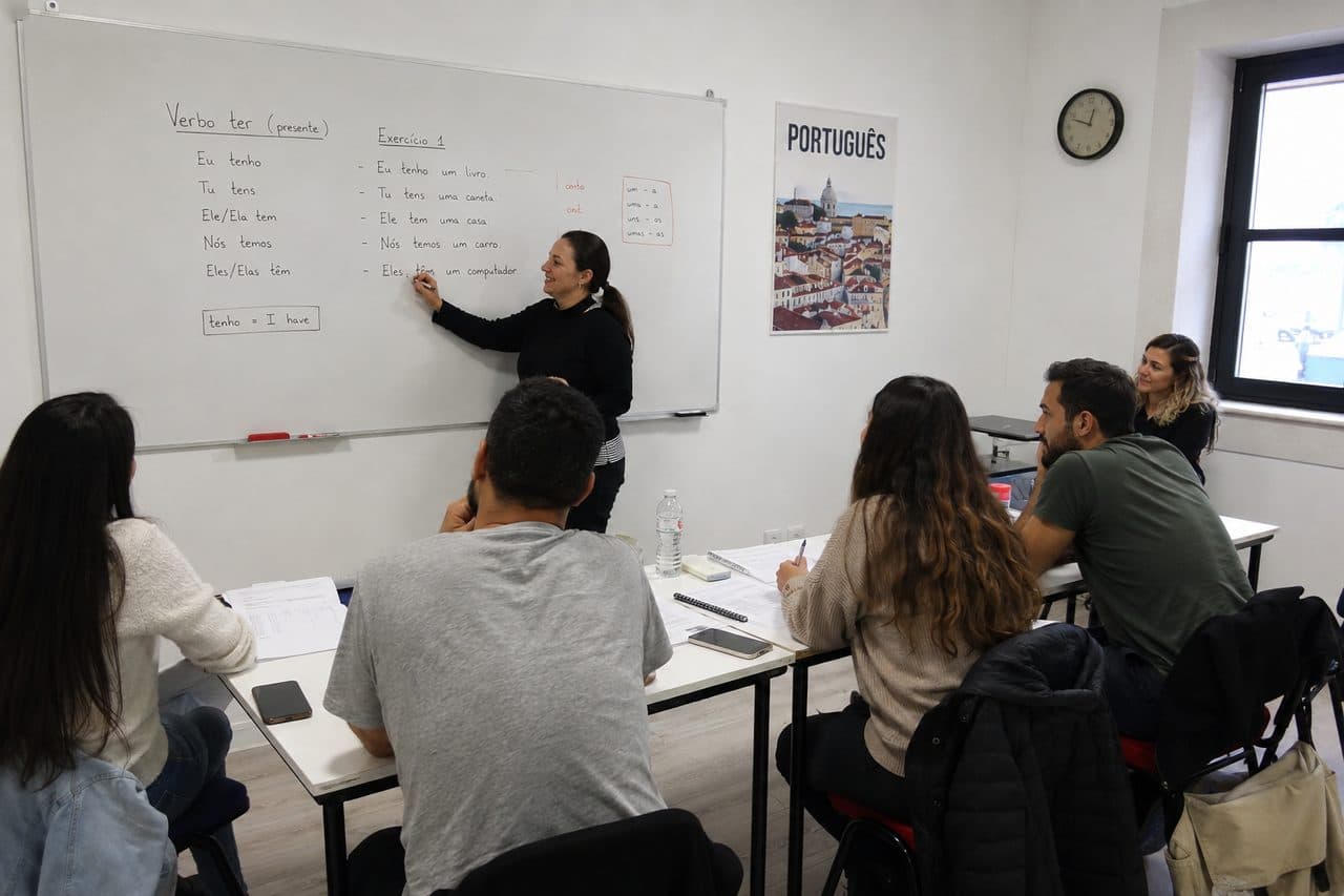 A Portuguese lesson in progress: the teacher writing verb conjugations on the whiteboard while students follow at their desks